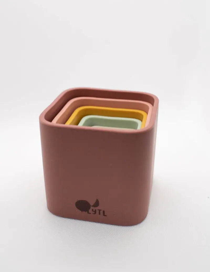 Colorful silicone stacking toy cups arranged in a pyramid shape. Children playing with silicone stacking cups, creating a tower. A close-up of a child’s hands nesting silicone stacking cups inside each other.