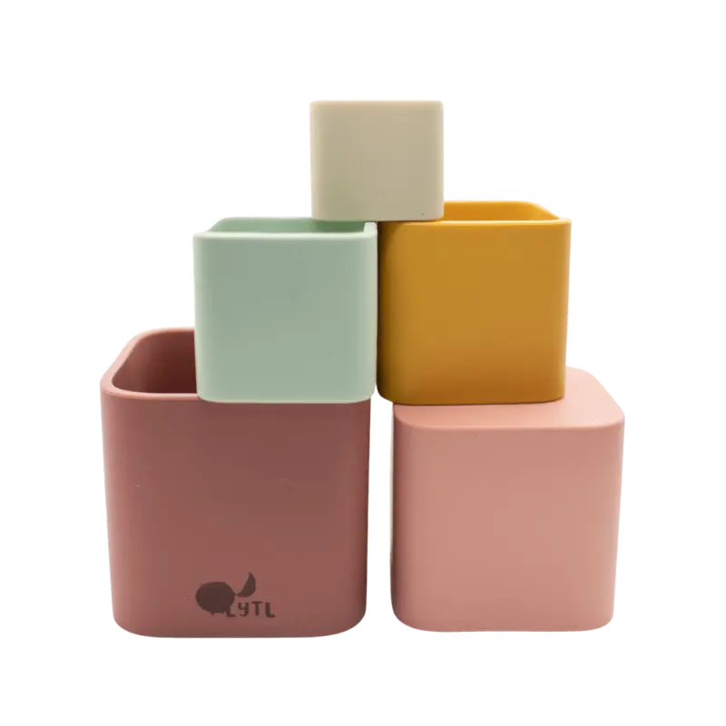 Colorful silicone stacking toy cups arranged in a pyramid shape. Children playing with silicone stacking cups, creating a tower. A close-up of a child’s hands nesting silicone stacking cups inside each other.