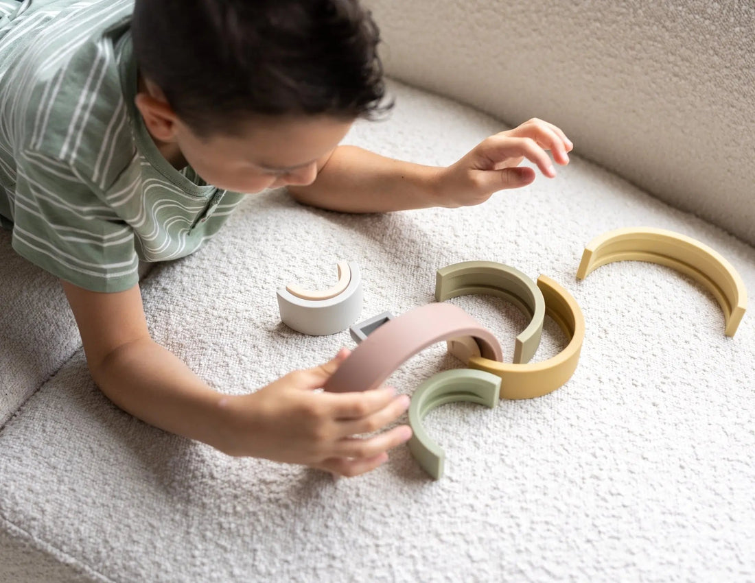 Young boy building with a silicone rainbow stacking toy, encouraging creativity and calm Montessori play