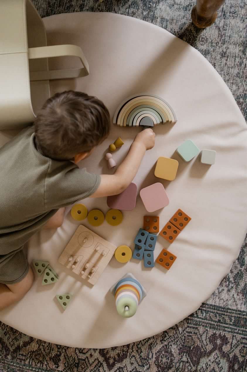 Boy playing with Lytl puzzle, rainbow, and stacking toys