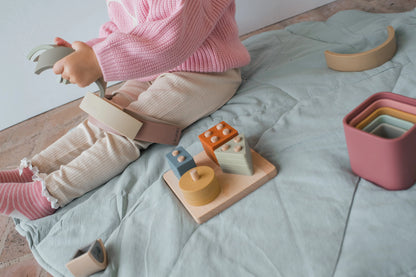 Toddler playing with rainbow stacker on cotton play mat