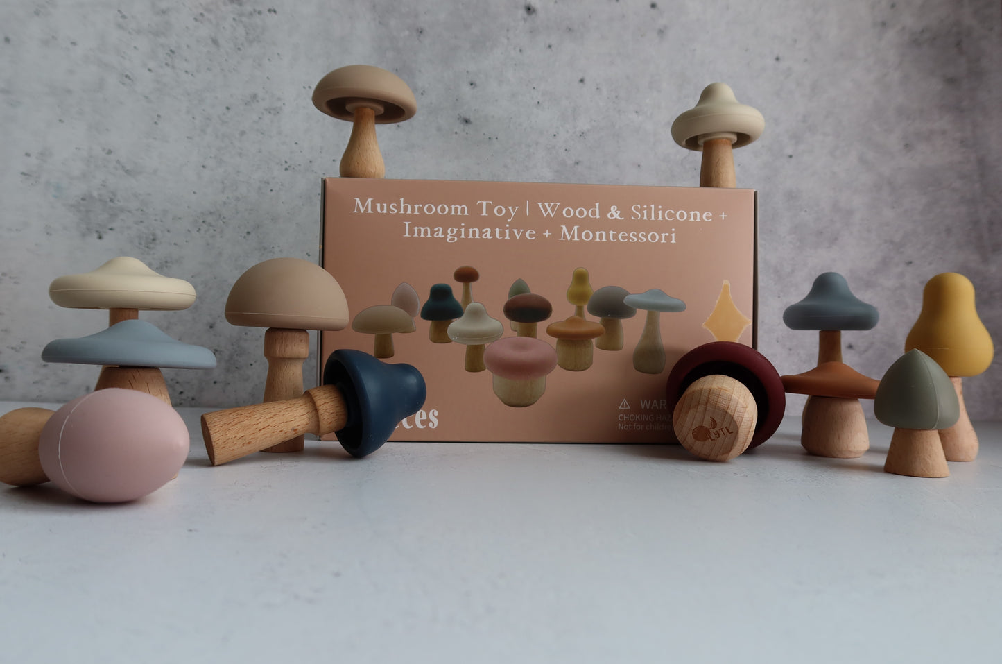 Wooden mushroom toys with a box labeled 'Mushroom Toy | Wood & Silicone' on a gray background. Non-toxic silicone and wood Montessori toddler toy for fine motor skill development