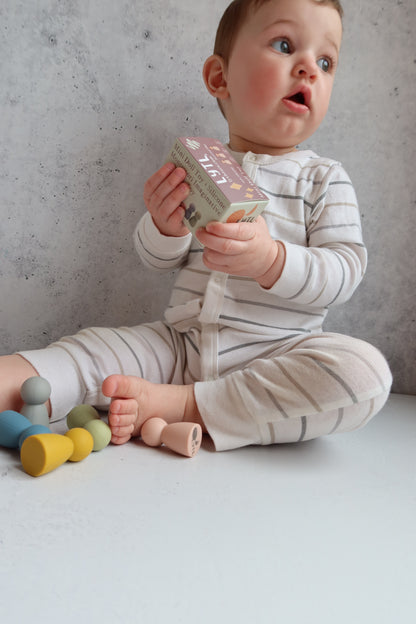 Baby playing with colorful silicone mini dols / peg montessori toys on a light-colored floor