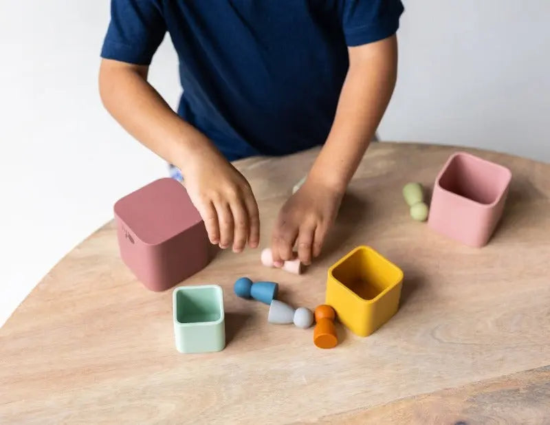 Silicone stacking cups being used in a sensory play activity. Parents and children playing together with silicone stacking cups. Silicone stacking cups being cleaned in a dishwasher.